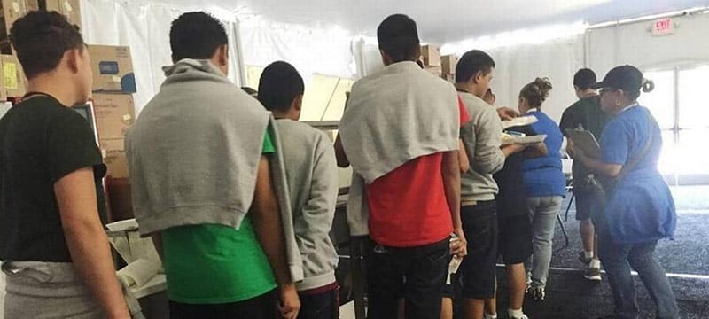 Adolescentes en un comedor de albergue recibiendo comida, representando la atenci&oacute;n a menores migrantes