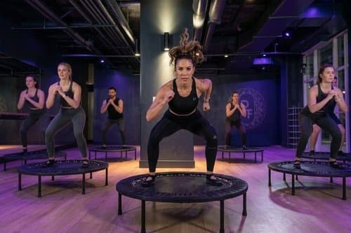 Personas entrenando con trampolines en un gimnasio dinámico