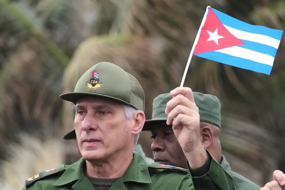 Hombre con uniforme militar sosteniendo bandera cubana durante una manifestación