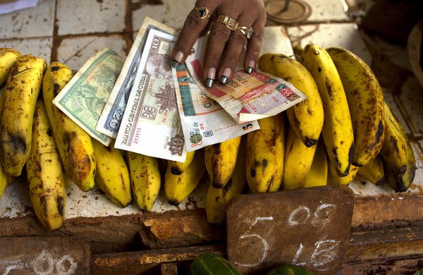Mano colocando billetes sobre plátanos en un mercado
