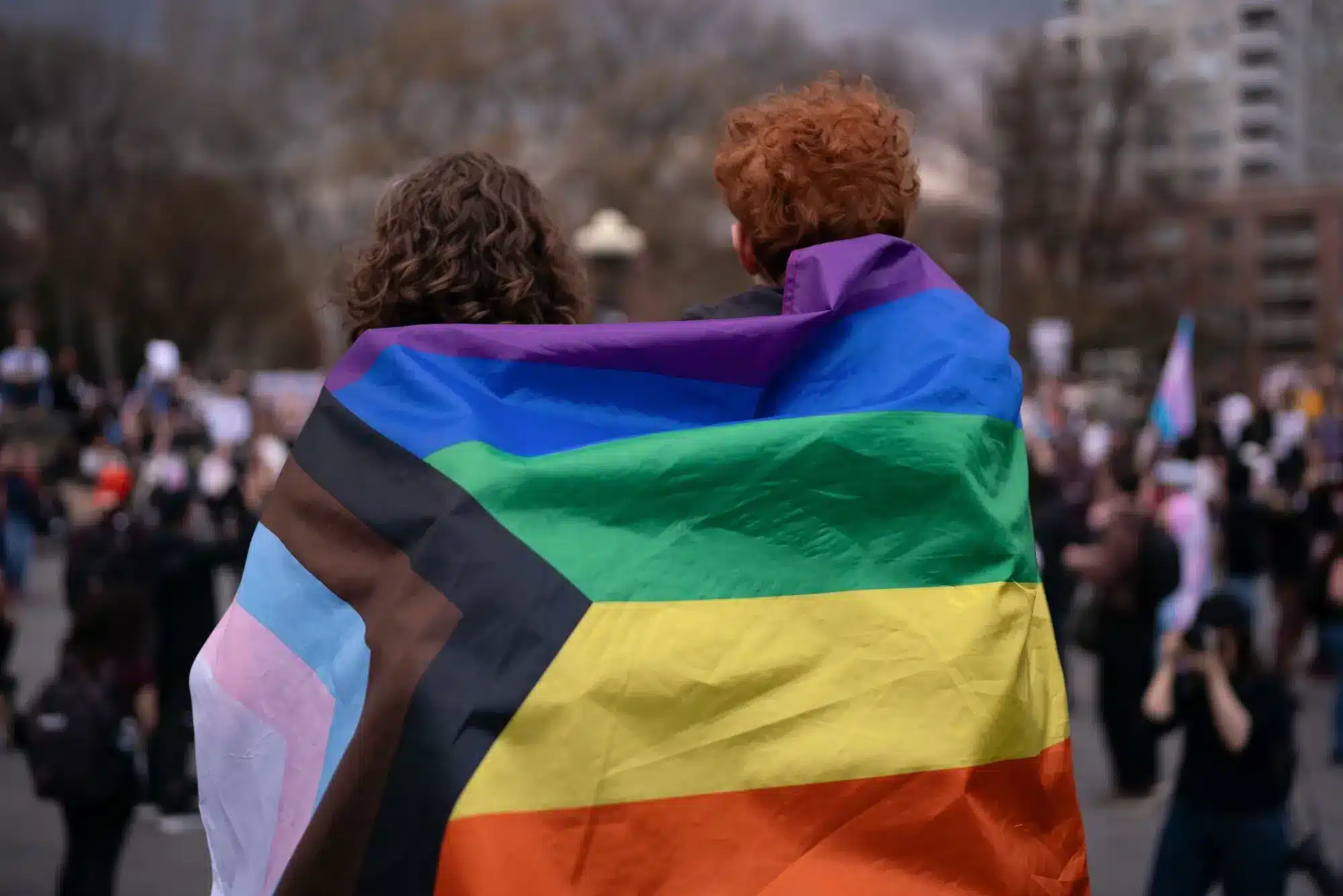 Personas envueltas en bandera del orgullo LGBTQ+ en una manifestación