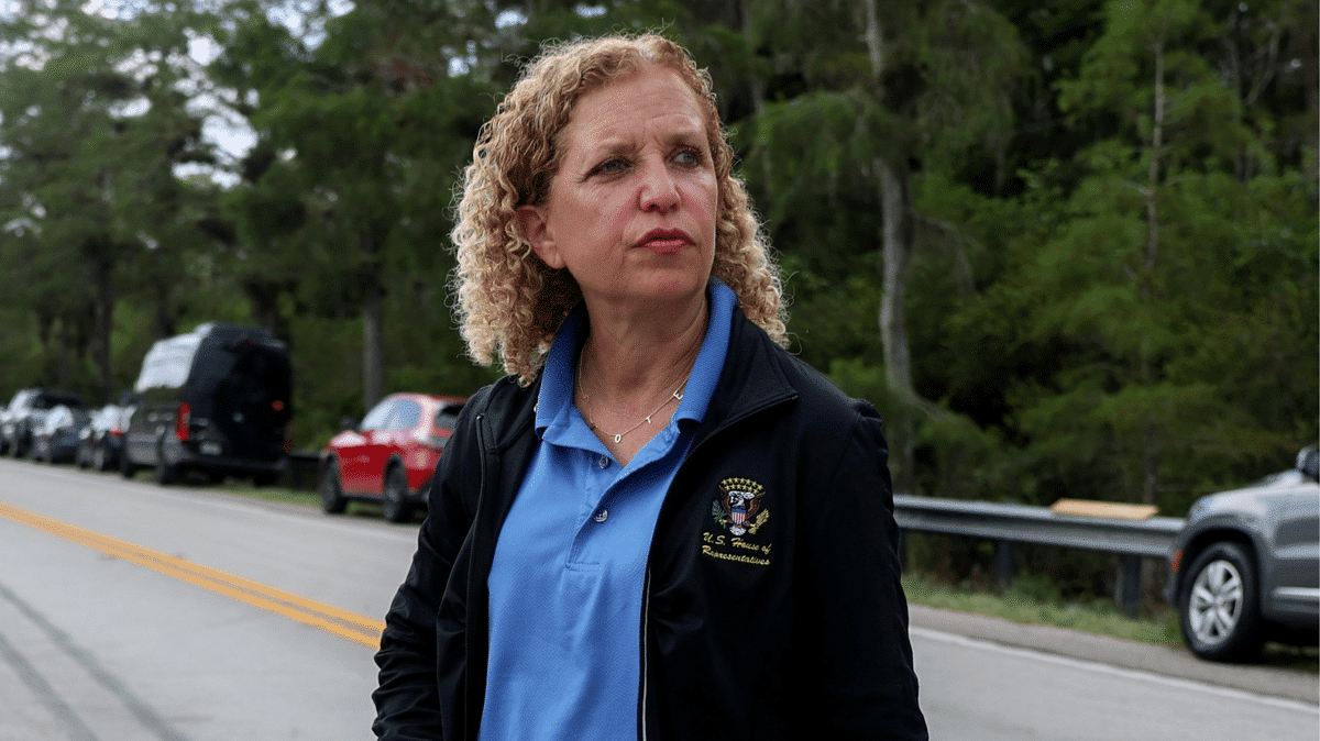 Debbie Wasserman Schultz de pie en una carretera con expresión seria