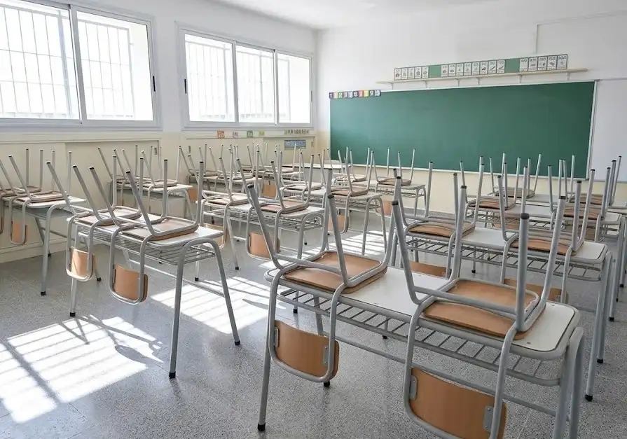Aula vacía con sillas apiladas, simbolizando el impacto de la crisis educativa