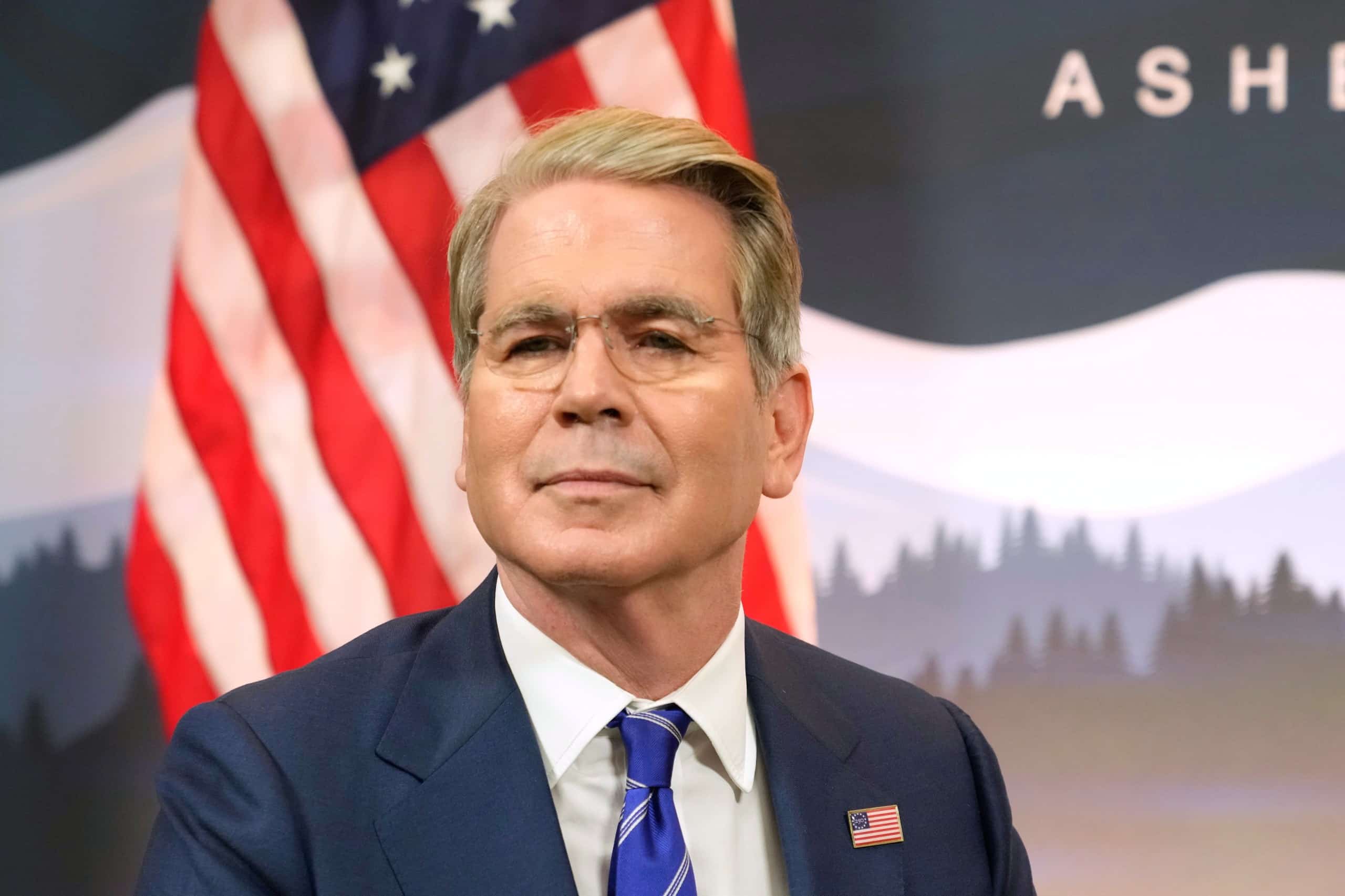 Scott Bessent con traje azul y bandera de Estados Unidos de fondo durante el G20