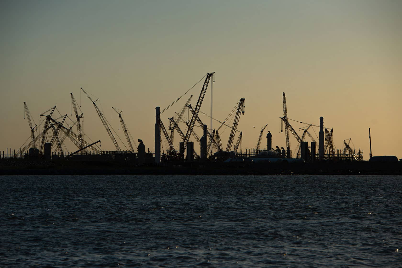 Grúas de construcción al atardecer en una zona industrial o portuaria