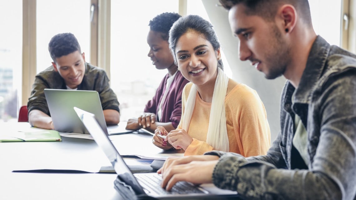 Estudiantes colaborando con computadoras portátiles en un entorno de aprendizaje