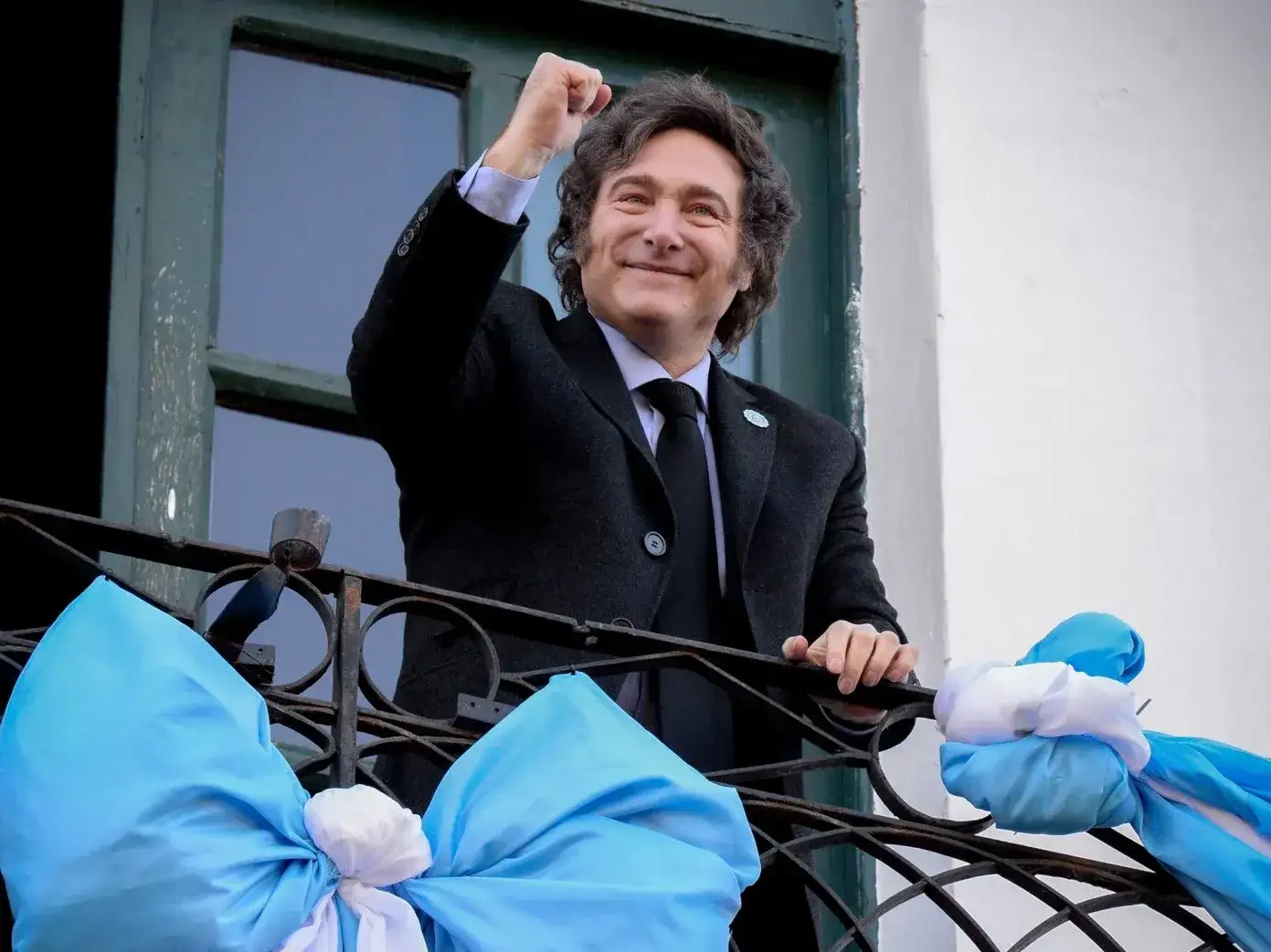 Javier Milei celebra desde un balcón con decoraciones azules y blancas