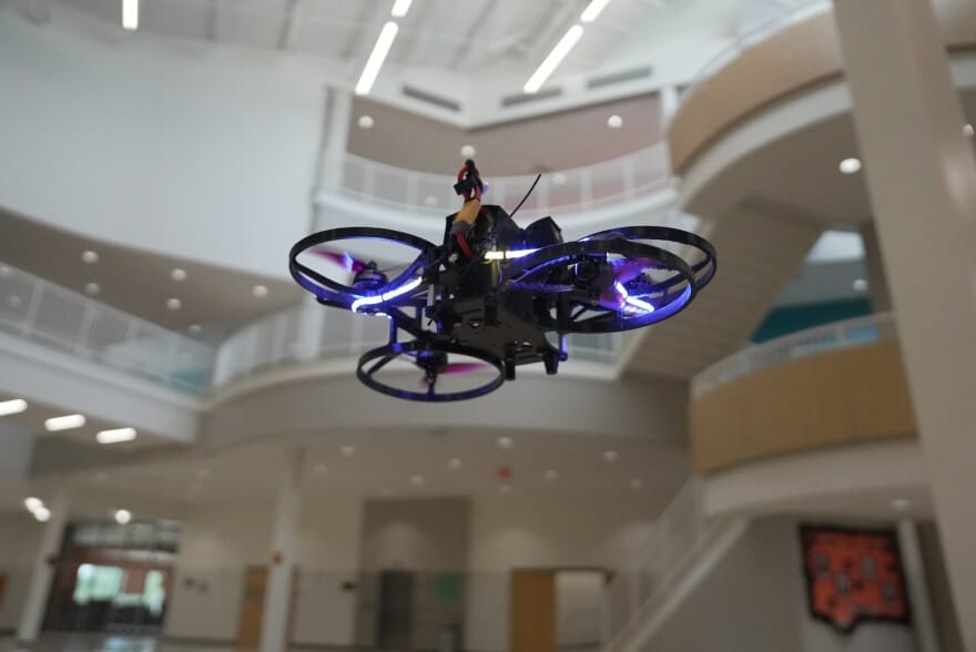 Dron volando en un pasillo escolar con luces LED