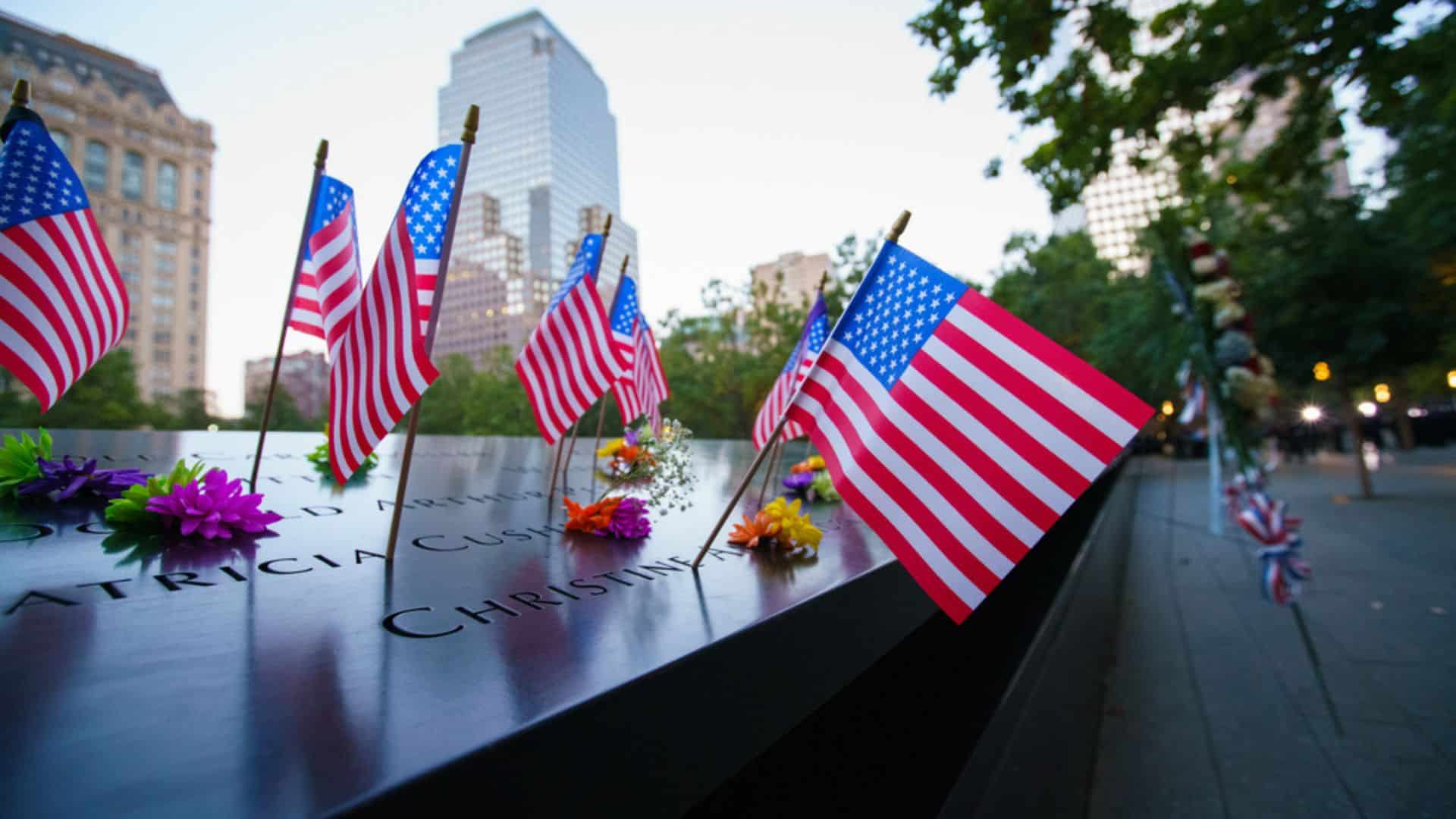 Banderines de Estados Unidos y flores alrededor del monumento conmemorativo del 9/11