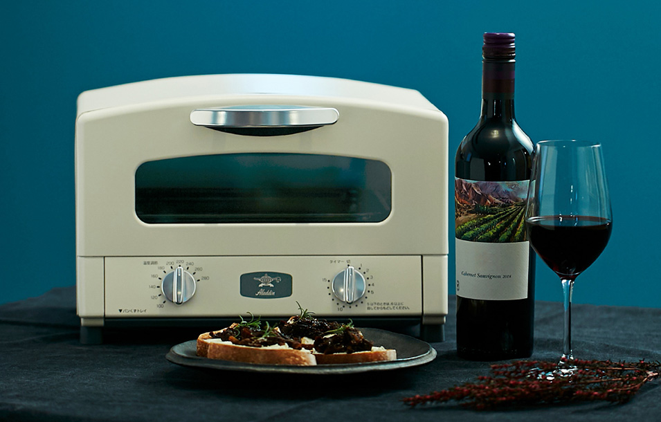 ผู้หญิงกำลังปิ้งขนมปังด้วยเตาอบ Aladdin สีขาวในห้องครัว