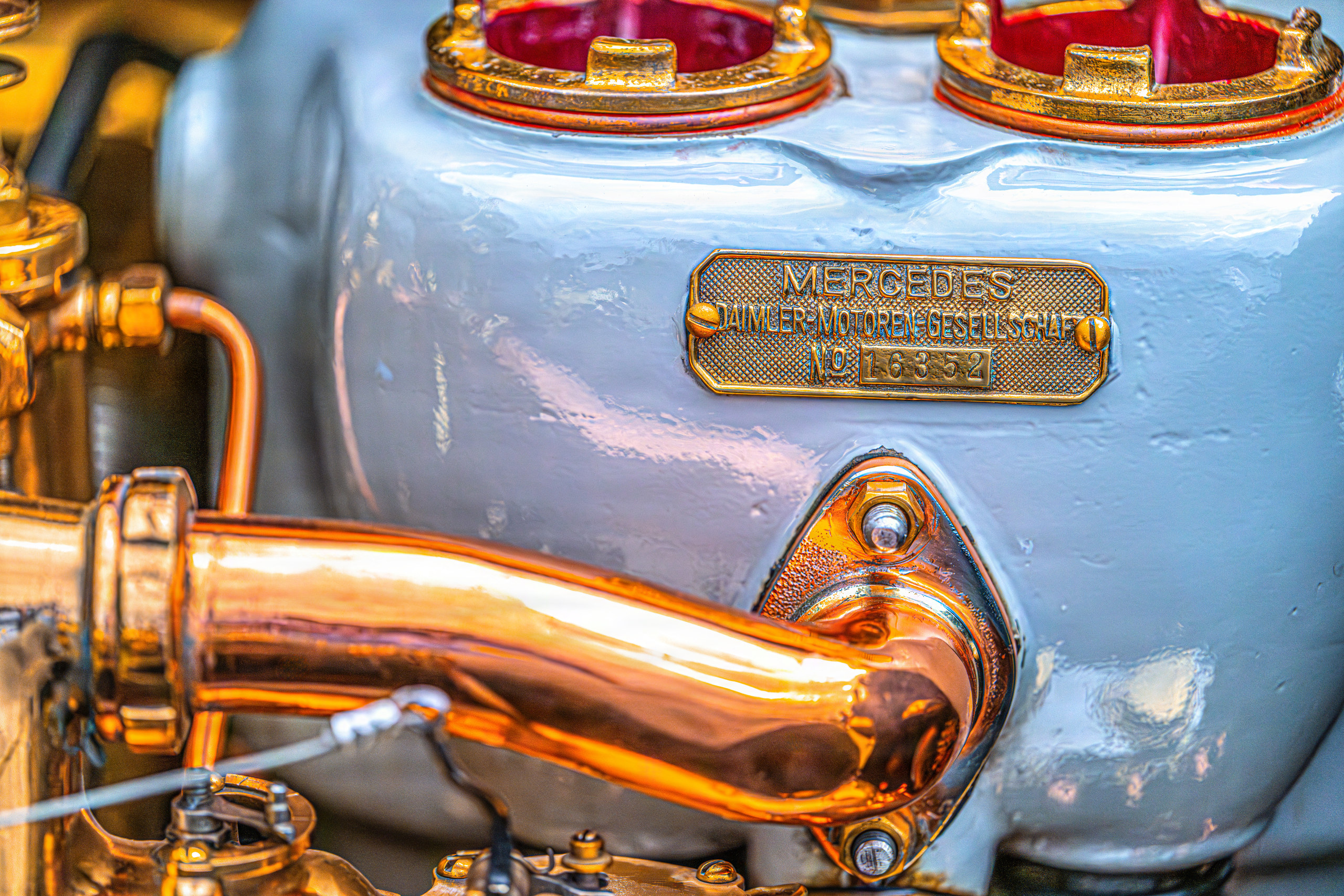 Brass maker's plate and copper elbow on a pale blue engine casting — fine art photography on aluminum