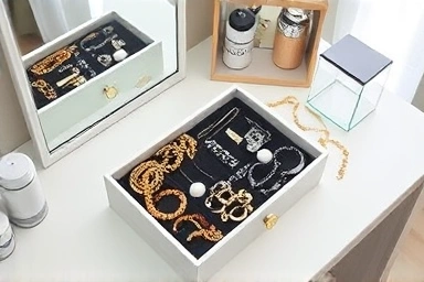 Elegant jewelry storage box with organized accessories on a vanity.