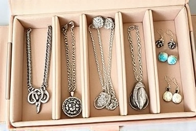 Close-up of jewelry organizer compartments showing neat storage of necklaces, earrings, rings.