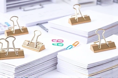 Organized desk with metal double clips holding papers.