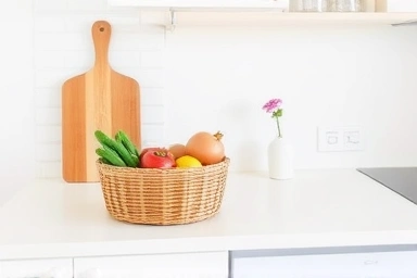 Kitchen counter with rattan basket of fruits and vegetables.