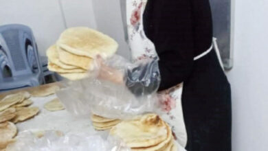سيدة تقوم بتغليف خبز لتوزيعه كمساعدات على المحتاجين بالغور الشمالي-(ارشيفية)