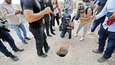 الشرطة الإسرائيلية والصحفيون يتجمعون حول حفرة استخدمها ستة أسرى للهروب من سجن جلبوع.-(ا ف ب)