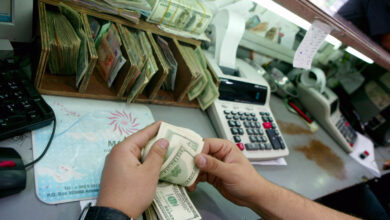 صيرفي يحصي أموالا في محله بوسط البلد - (الغد)