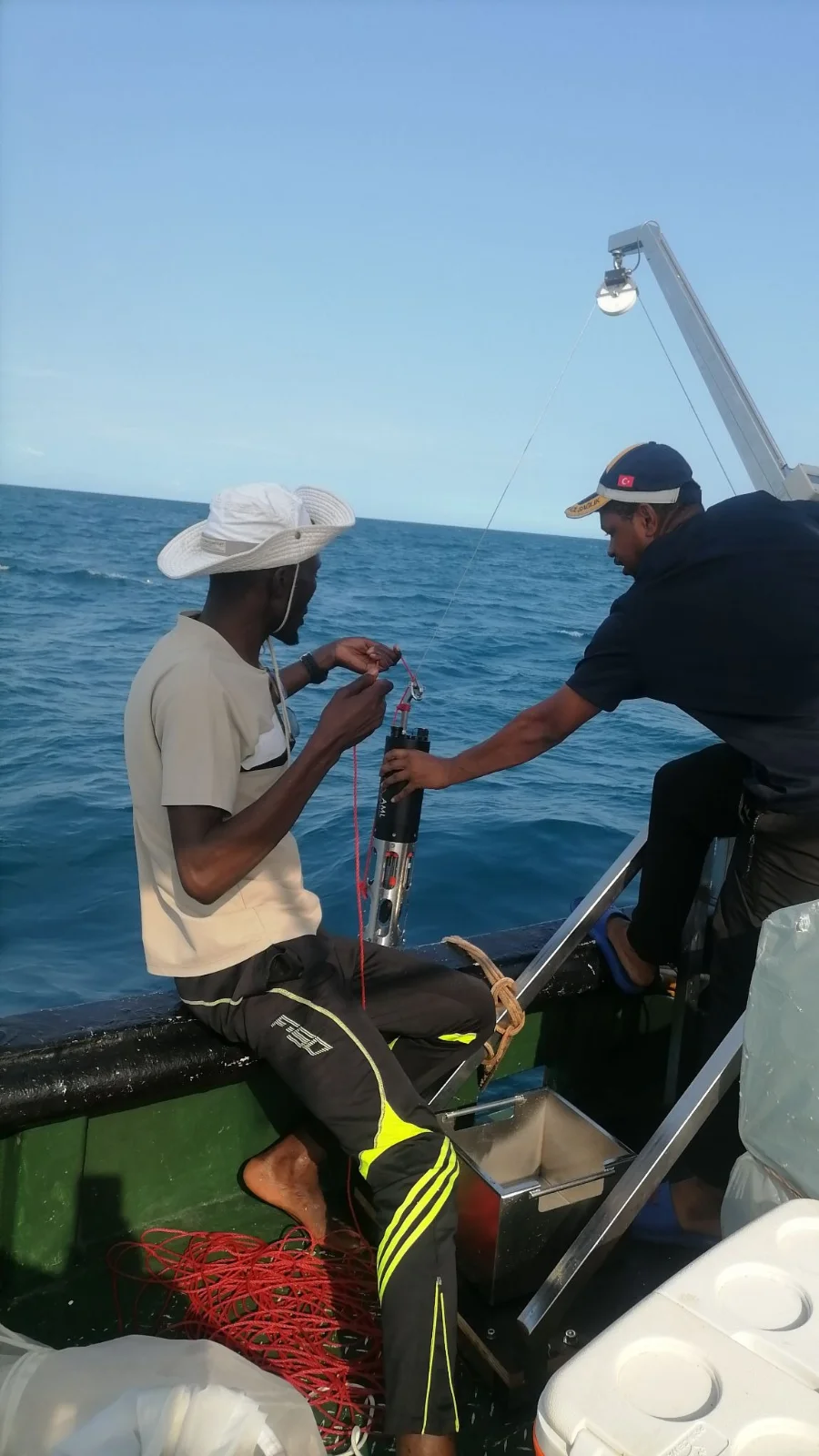 Two researchers on a small boat attach an AML instrument to a line before lowering it over the side.