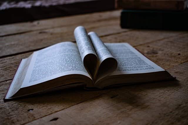 Book on wooden table with pages folded in heart shape