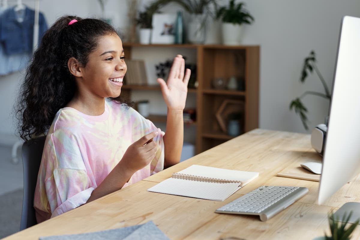 Student waving at teacher in online tuition