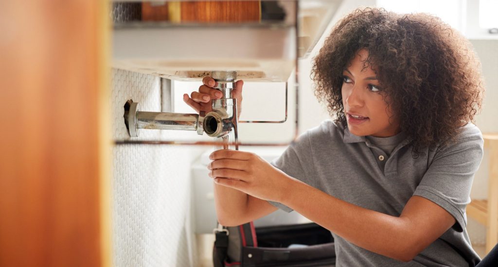 a young woman from plumbing industry, fixing a pipe