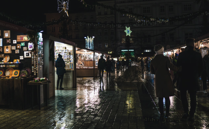 People in winter coats walking through Kraków at night during winter (pub crawl vibes)