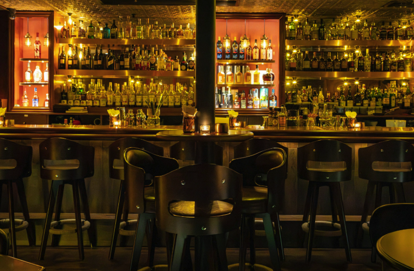 Warm, dimly lit bar interior with stools and