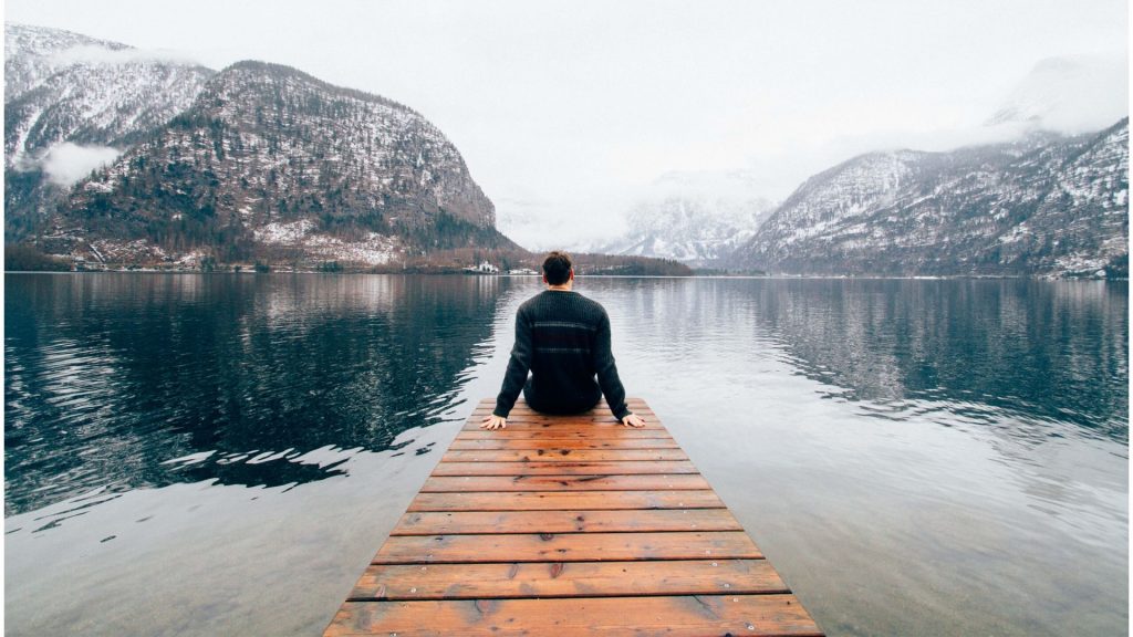 man sitting at the edge of a ramp in the middle of a river.