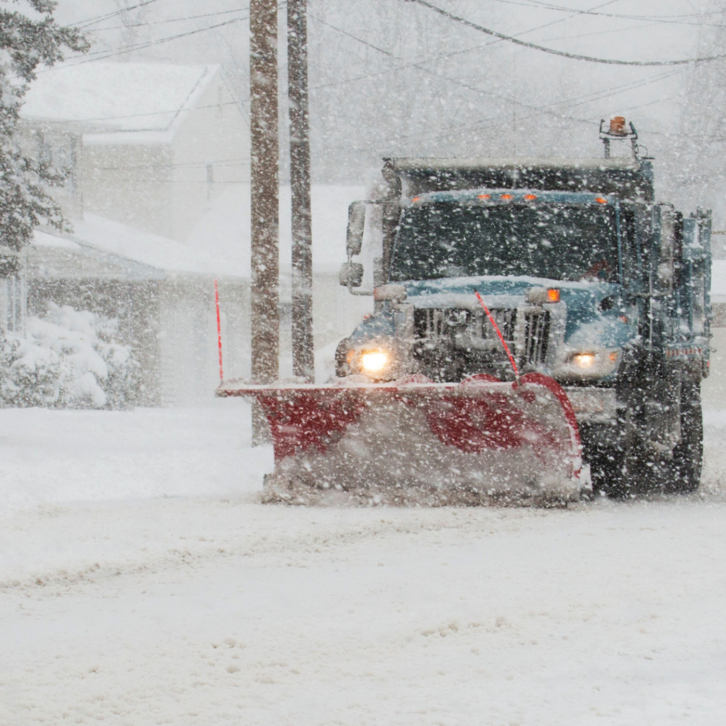 Snow plow clearing streets during a snow storm