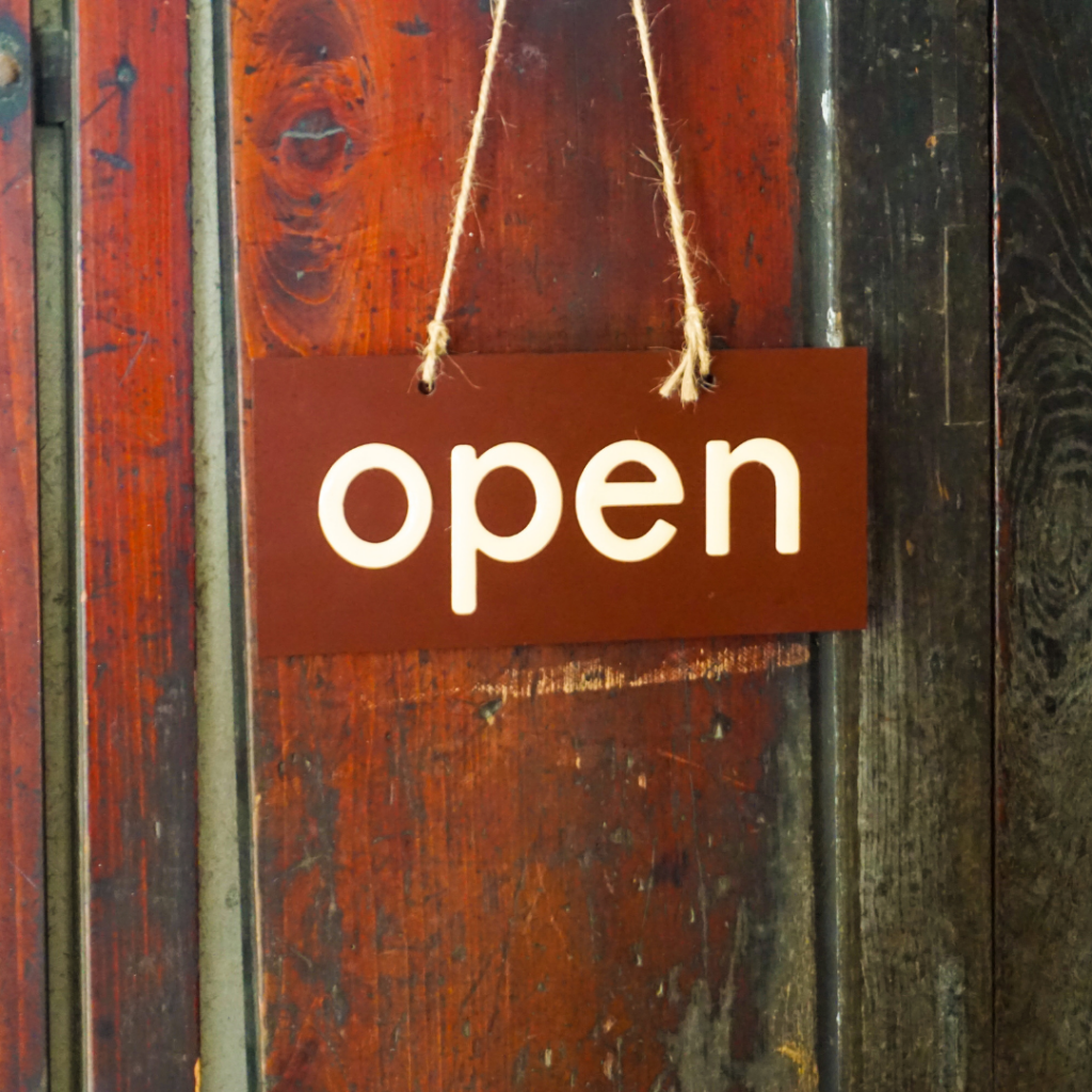 Open sign hanging on a wooden wall hinting to help influx of calls.