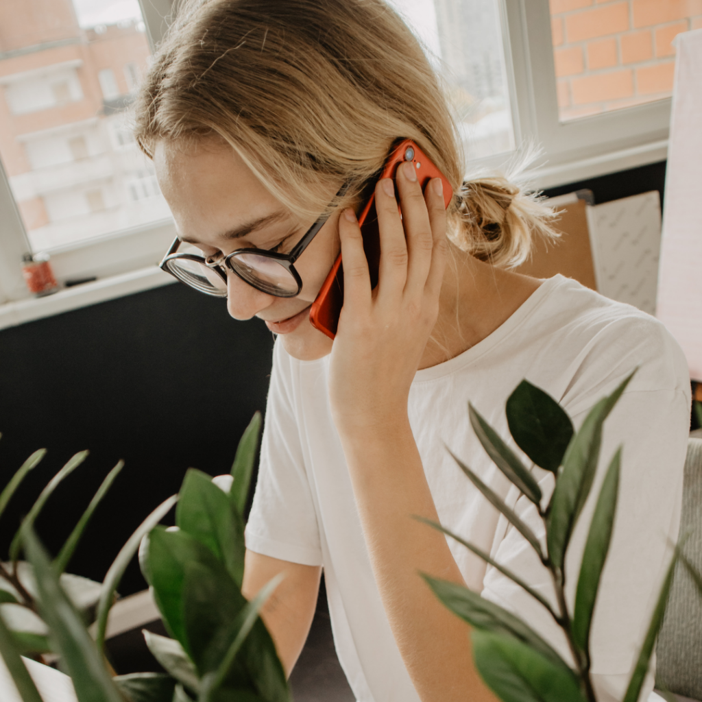 Woman on the phone next to plants.