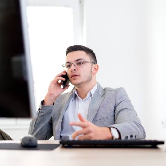 Man on the phone looking at the computer helping a customer with custom scripting and active responses.