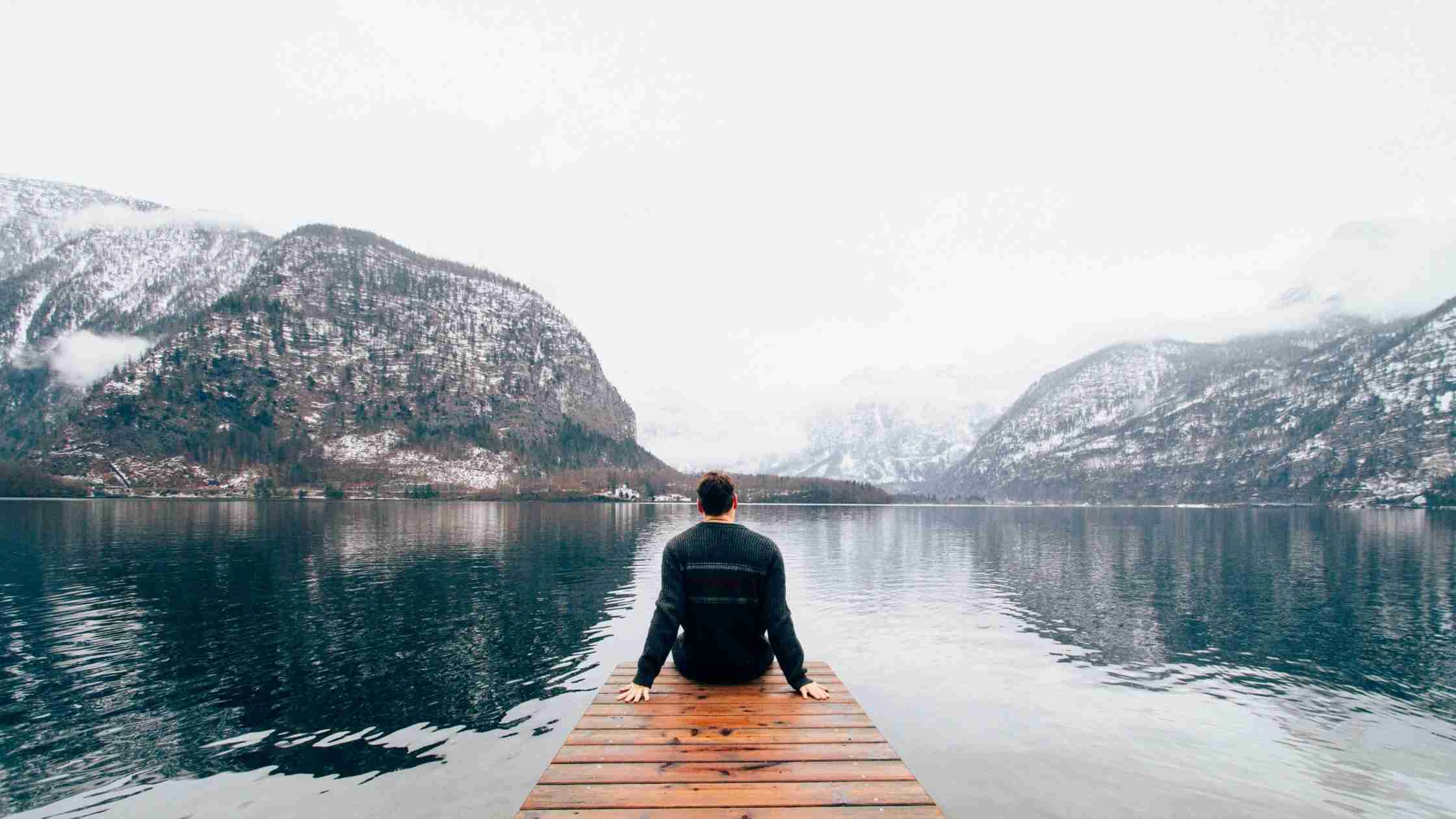 Man sitting on a deck, over looking a lake, working from Anywhere