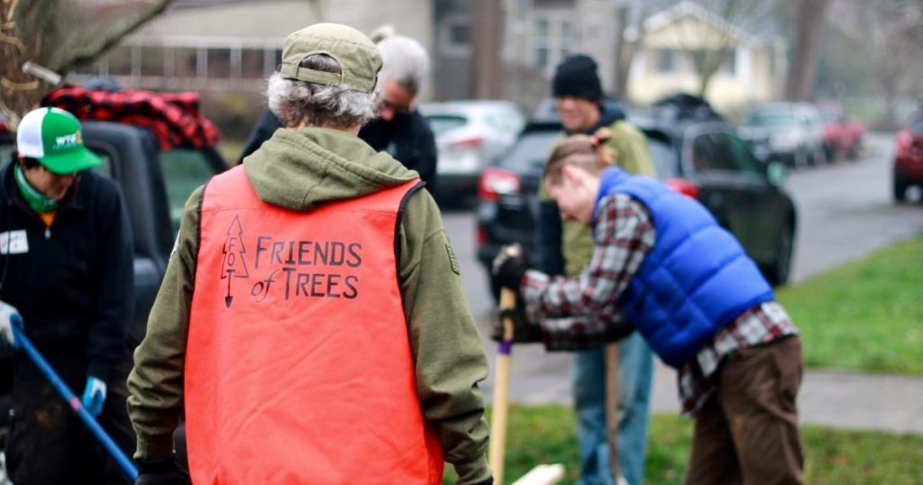 Male volunteer tree planting with group of people