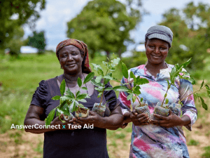 Two women standing holding trees in Africa to combat desertification