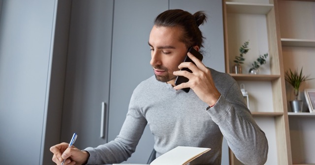 man working efficiently by talking on phone and writing down notes