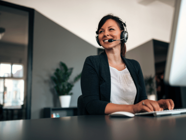 woman at desk talking typing with headset on