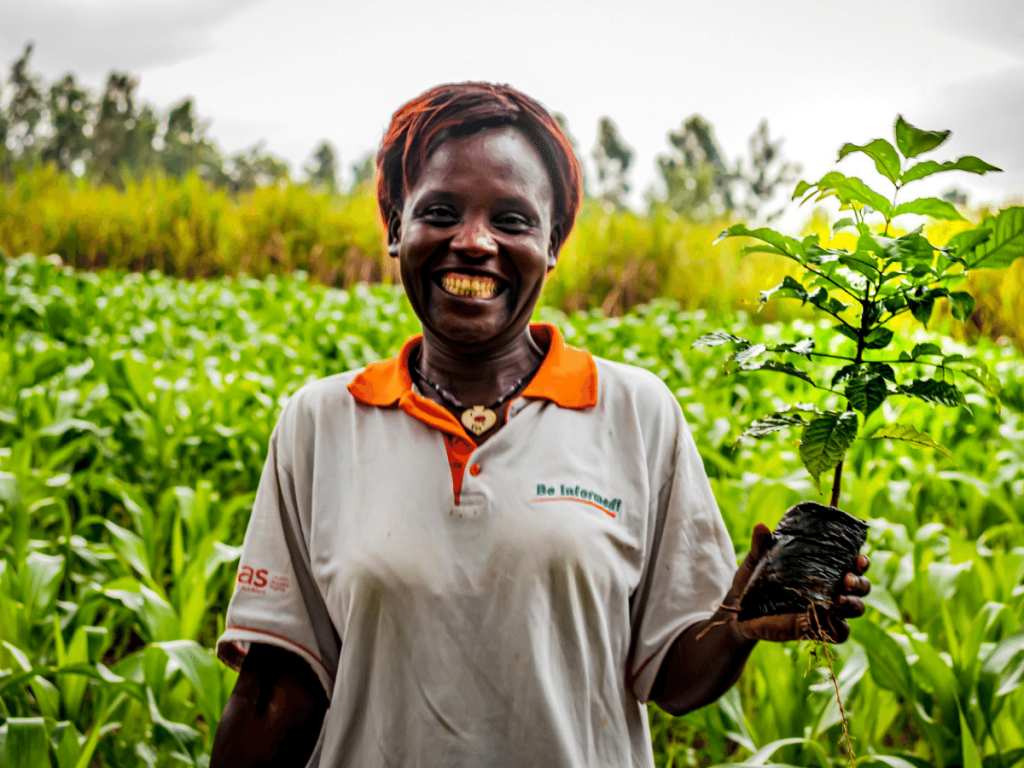 woman smiling with treeling in food forest