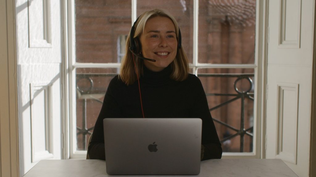 Smiling virtual receptionist with headset at desk working from virtual call cneter