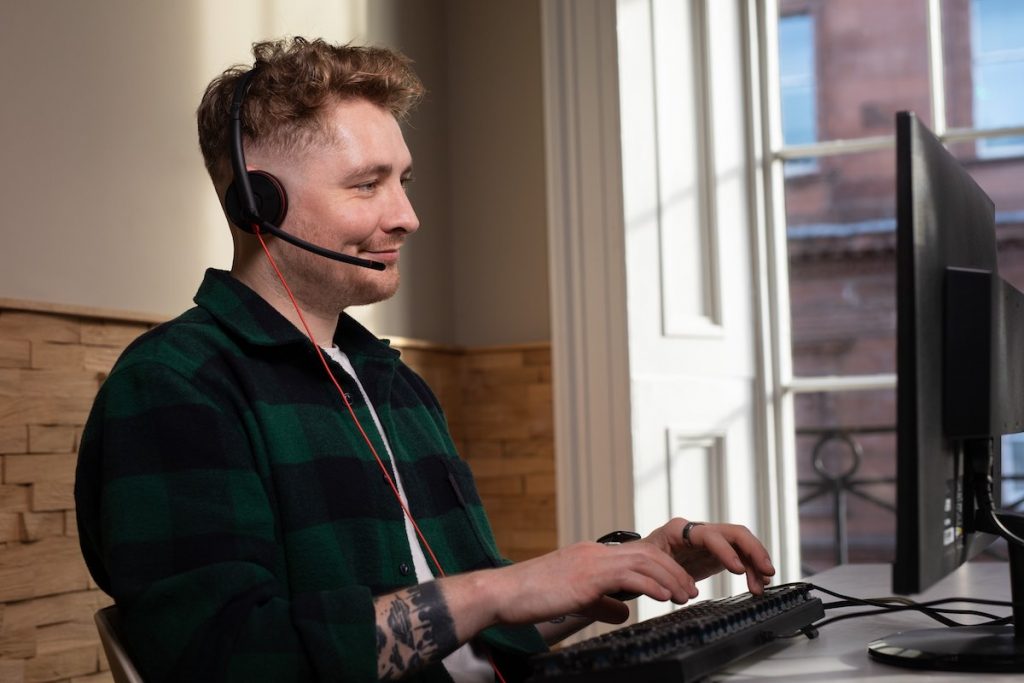 Man working as virtual receptionist with headset and desktop monitor in home setting