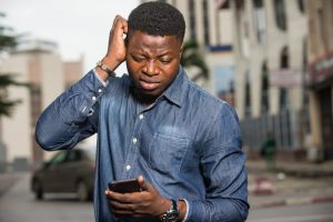 Man looking at smartphone trying to speak to a message-answering service