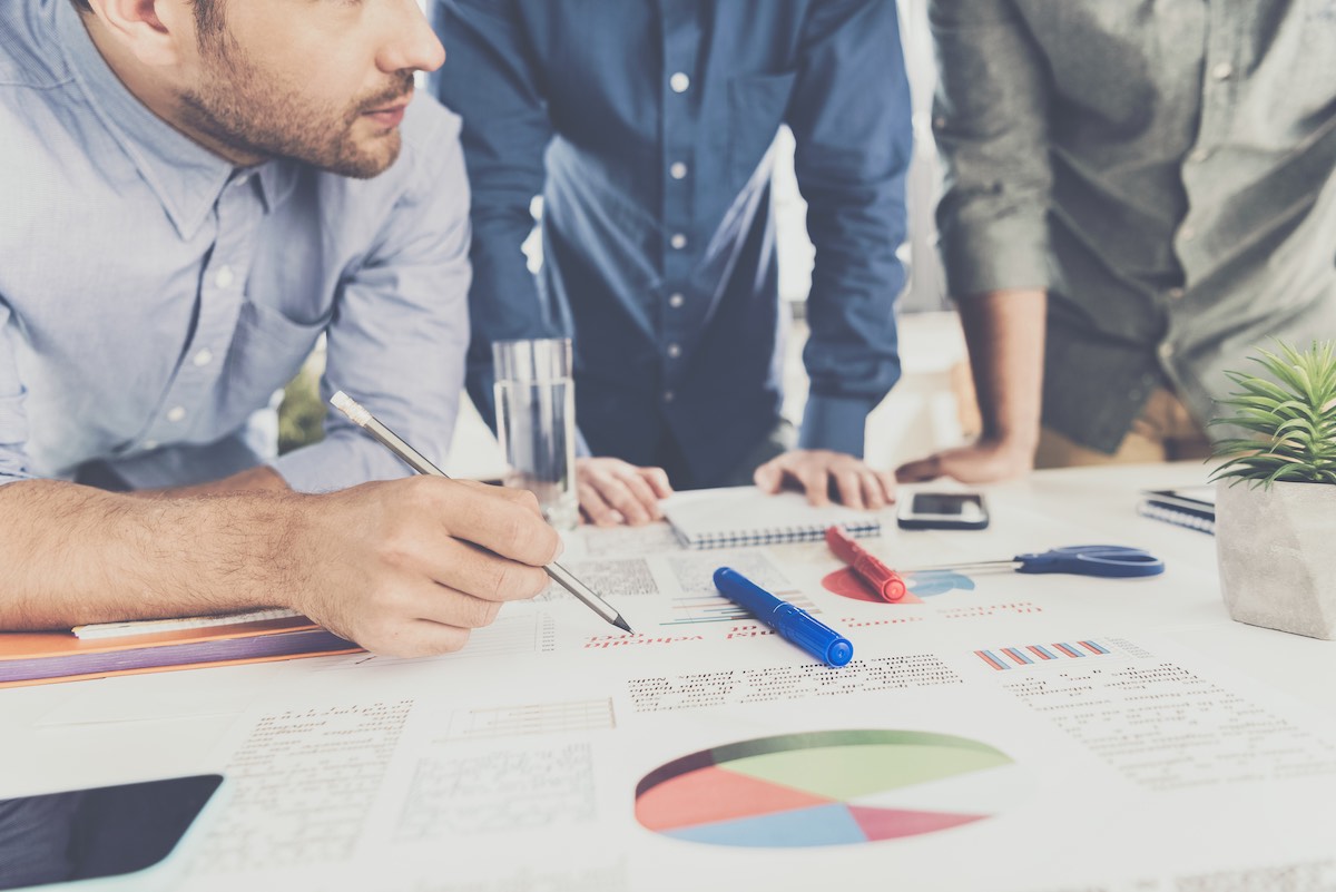 A small business team looking over graphs and figures splayed out on a desk.