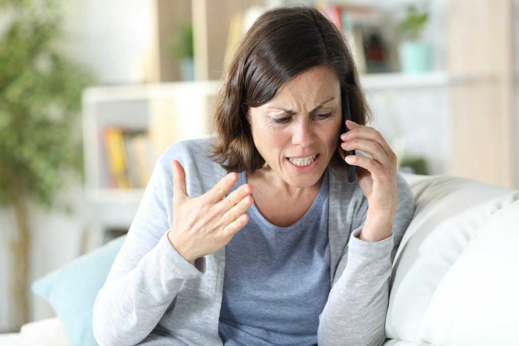 A frustrated customer on the phone with a long hold time, while employees are busy with other tasks