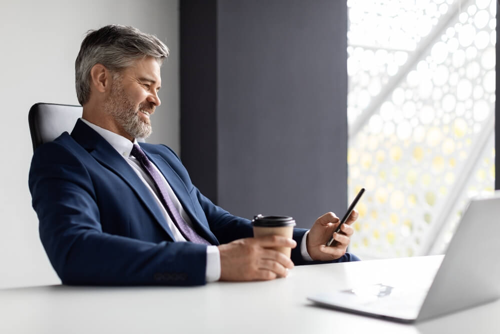 Manager smiling looking at phone at desk