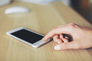 Fingers pressing a smartphone to forward a call