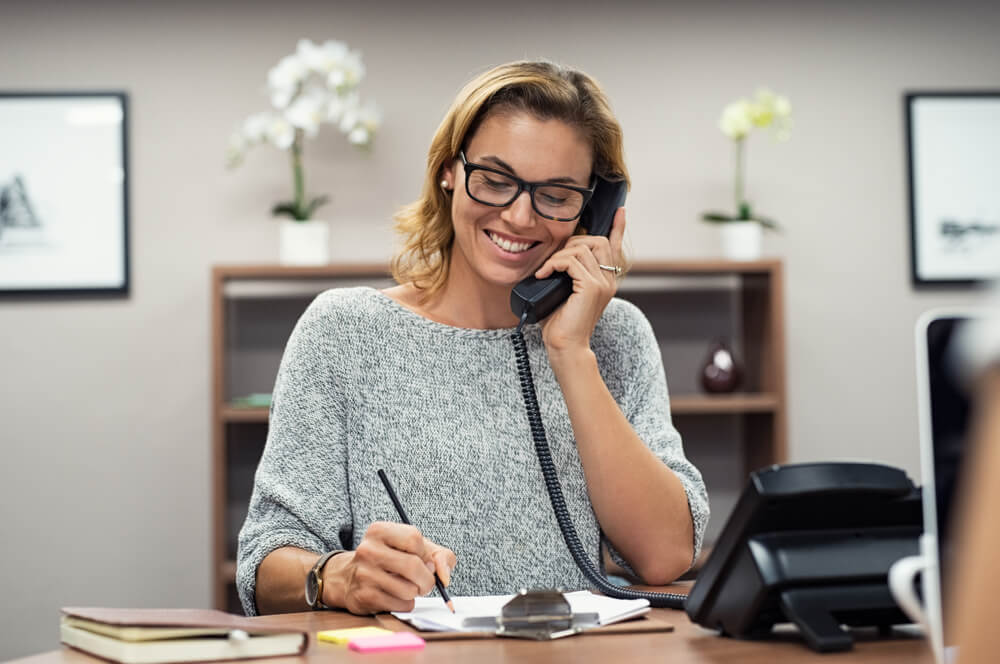 Smiling receptionist on phone forwarding a call 