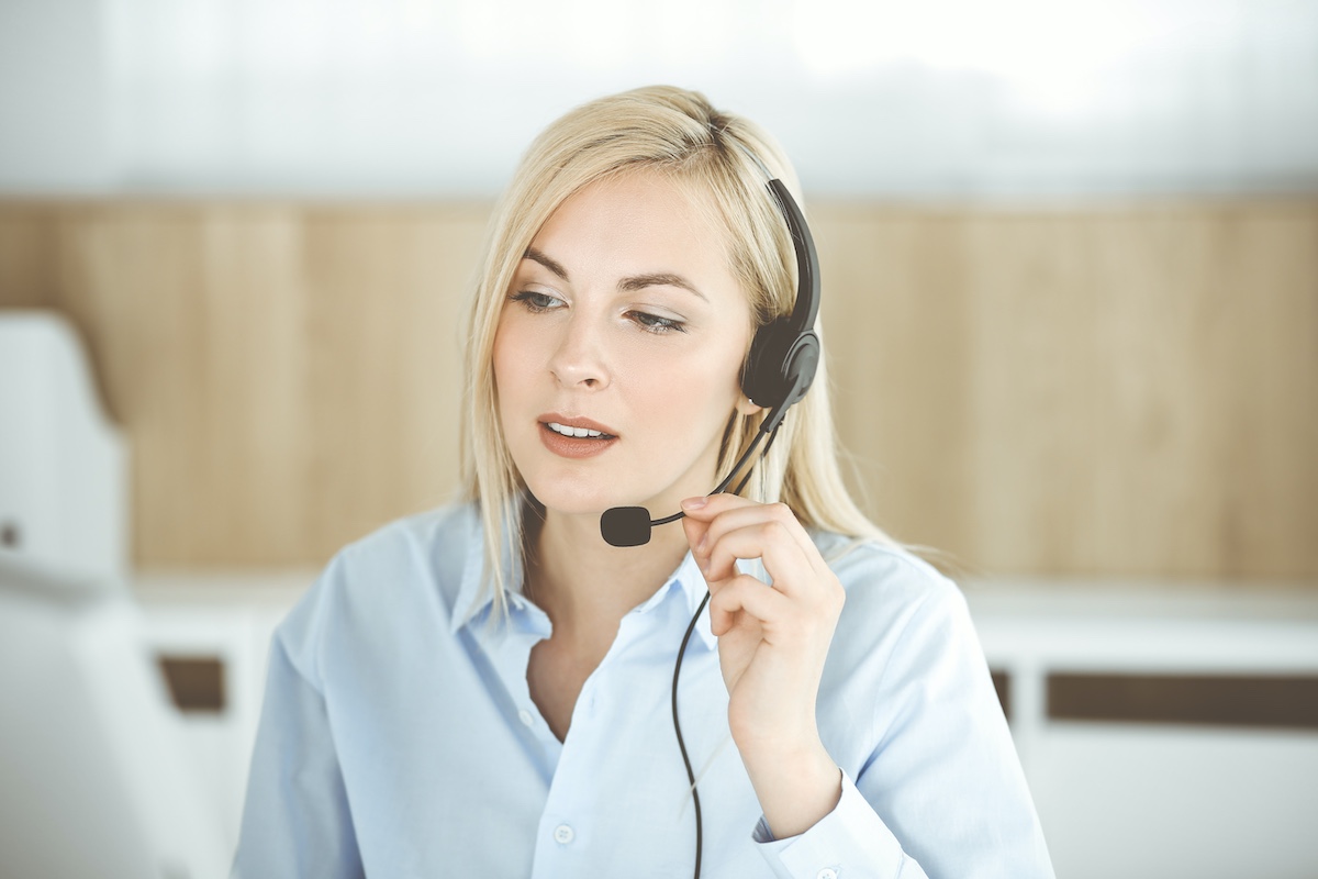 Smiling female receptionist taking calls for call centre service