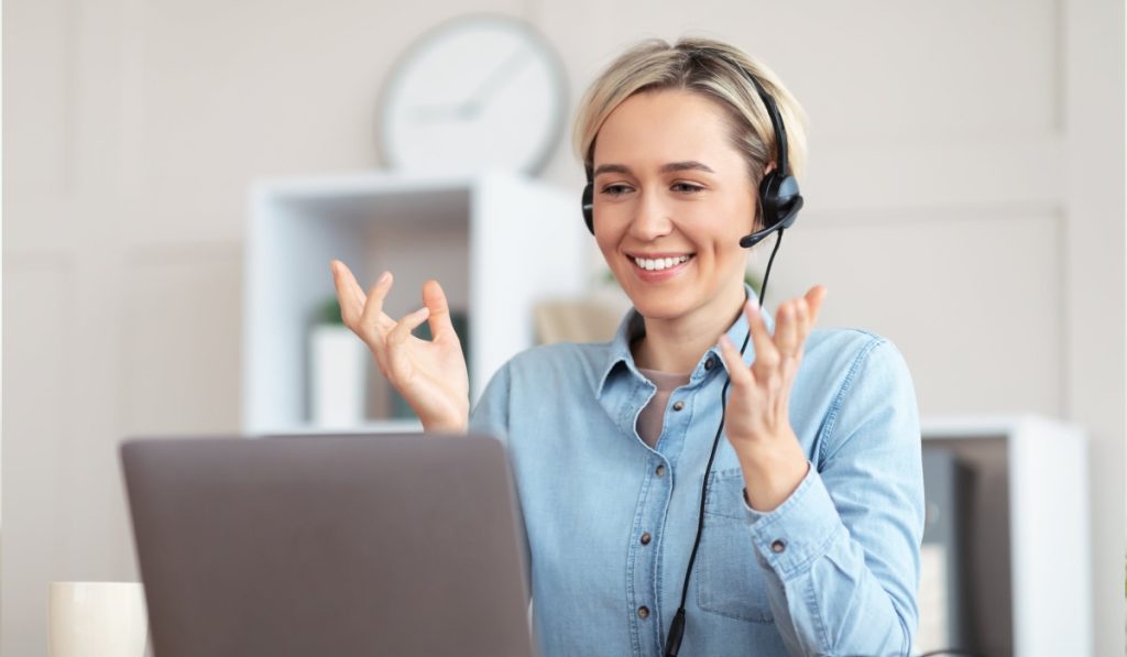 Smiling virtual receptionist at laptop w headset