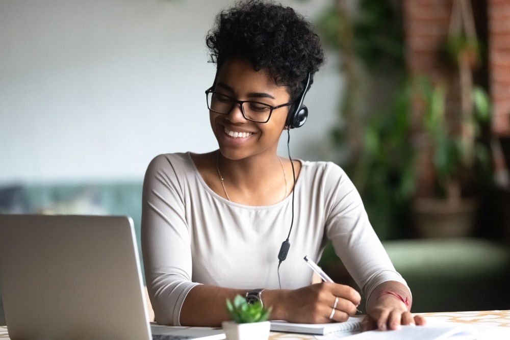 Female receptionist with headset in home setting smiling at laptop